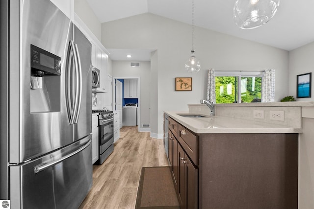 kitchen featuring sink, vaulted ceiling, dark brown cabinets, appliances with stainless steel finishes, and washer / clothes dryer