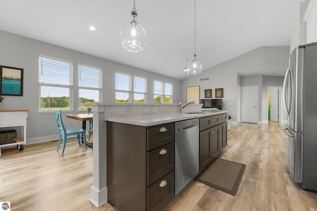 kitchen featuring stainless steel appliances, hanging light fixtures, dark brown cabinets, and a center island with sink