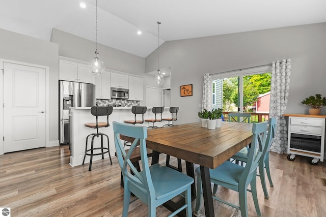 dining space featuring high vaulted ceiling and light wood-type flooring