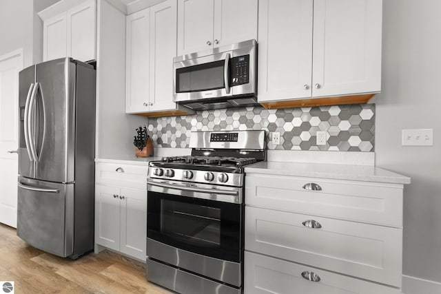 kitchen featuring white cabinetry, appliances with stainless steel finishes, backsplash, and light hardwood / wood-style flooring