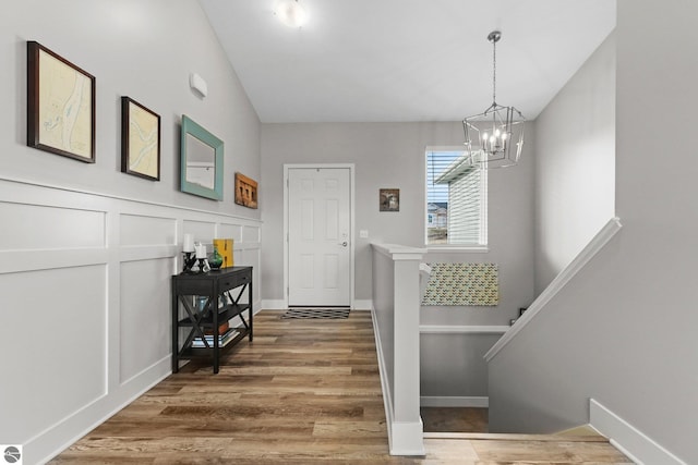 stairway with wood-type flooring, vaulted ceiling, and a notable chandelier