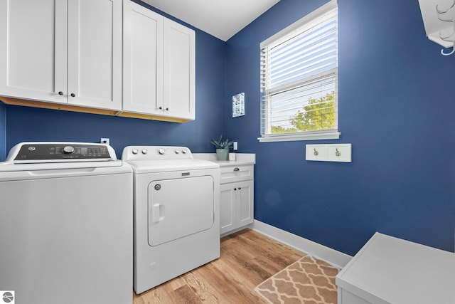 washroom featuring cabinets, washer and dryer, and light hardwood / wood-style flooring