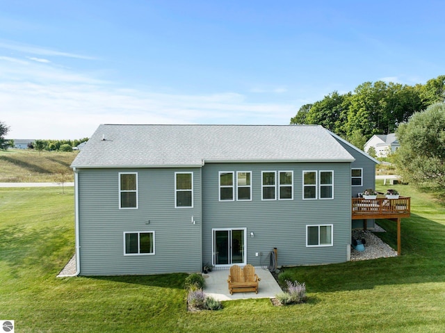 rear view of house featuring a patio, a deck, and a lawn