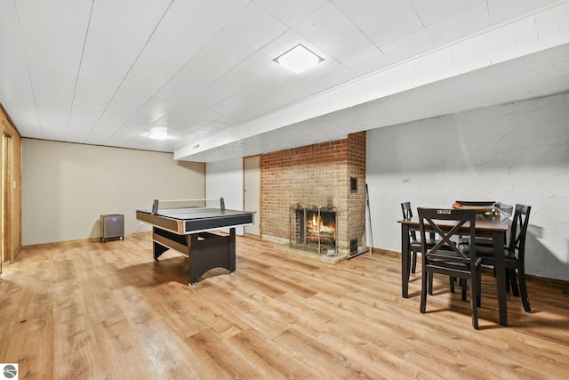 recreation room featuring a brick fireplace and light hardwood / wood-style flooring