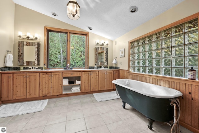 bathroom with a tub to relax in, vaulted ceiling, wooden walls, and a textured ceiling