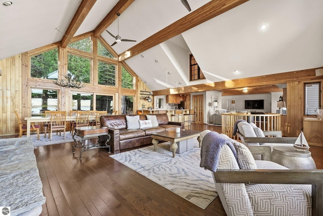 living room with ceiling fan, high vaulted ceiling, wood-type flooring, beamed ceiling, and wood walls