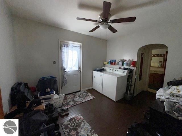 clothes washing area with washing machine and dryer, ceiling fan, and dark hardwood / wood-style flooring