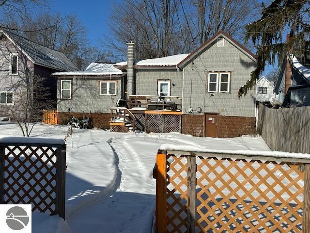 snow covered rear of property featuring a wooden deck