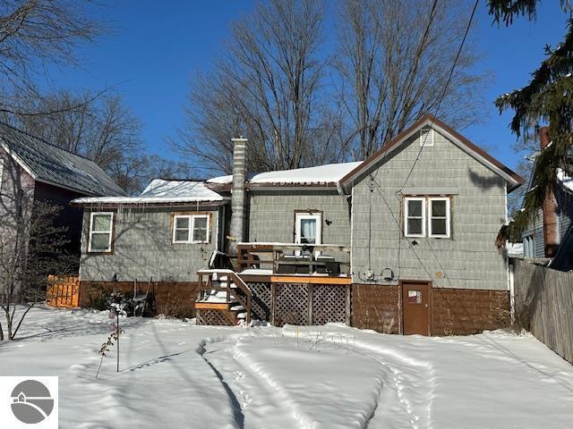 snow covered back of property with a wooden deck