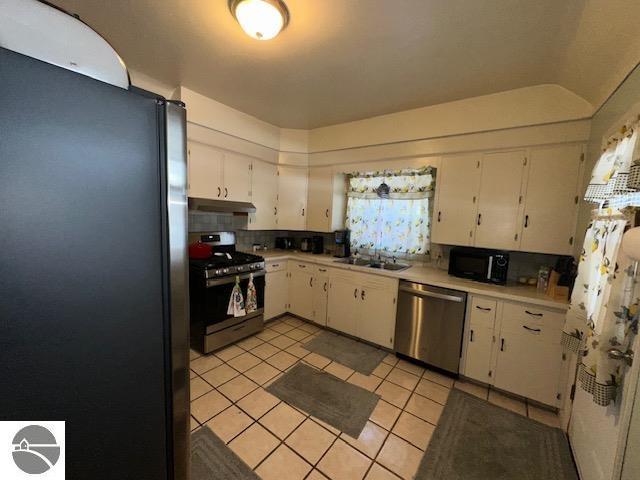 kitchen featuring sink, appliances with stainless steel finishes, white cabinetry, tasteful backsplash, and light tile patterned flooring