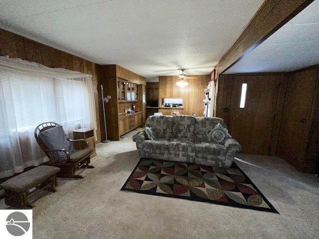 carpeted living room with beamed ceiling, plenty of natural light, and wood walls