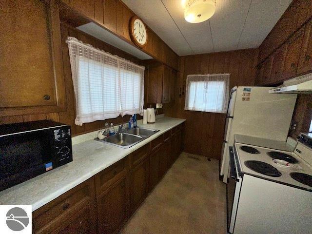 kitchen featuring white range with electric cooktop, sink, and wood walls