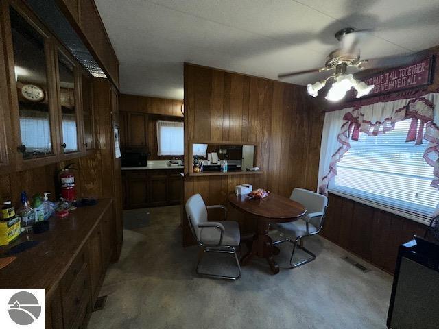 dining room with ceiling fan and wood walls