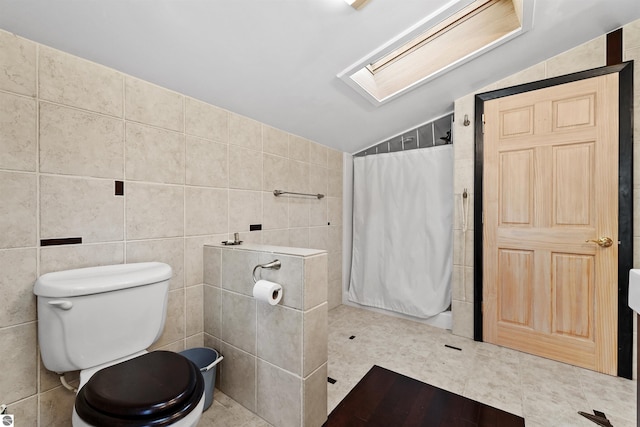 bathroom featuring toilet, lofted ceiling with skylight, and tile walls