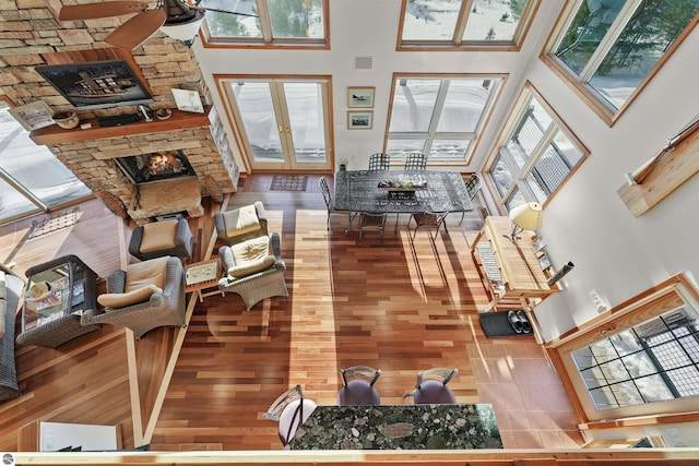 living room with french doors, a stone fireplace, a high ceiling, and a wealth of natural light