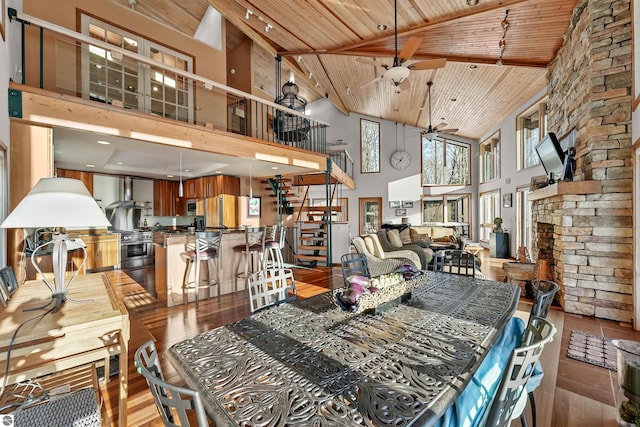 dining room with ceiling fan, a large fireplace, wood ceiling, and light hardwood / wood-style flooring