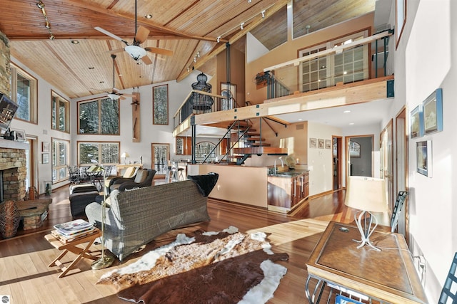 living room with wood ceiling, high vaulted ceiling, a stone fireplace, and hardwood / wood-style floors