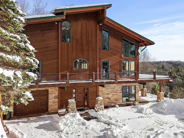 view of snow covered exterior featuring a garage and a balcony