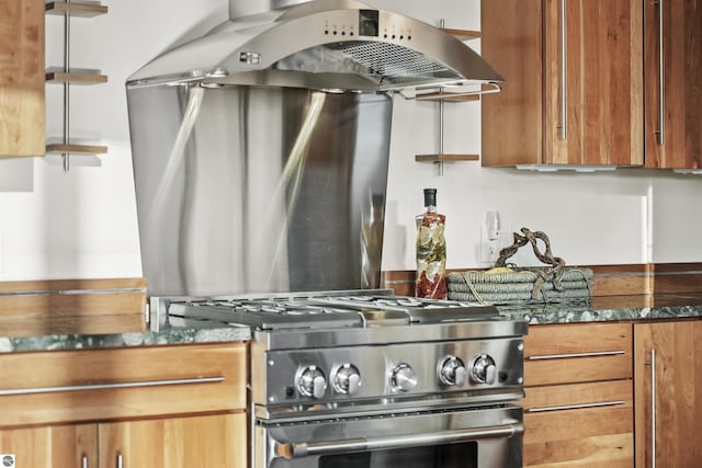 kitchen featuring gas range, island range hood, and dark stone counters