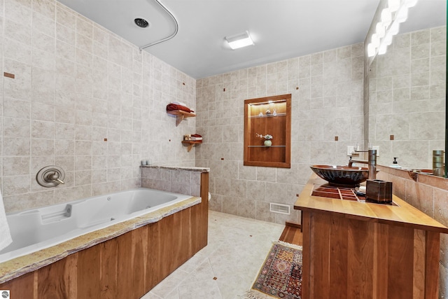 bathroom featuring tile walls, vanity, tile patterned floors, and tiled bath