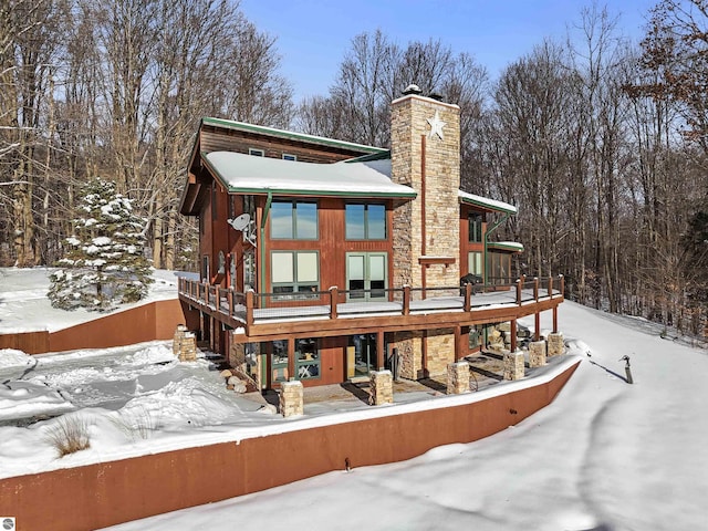 snow covered back of property featuring a wooden deck