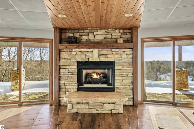 tiled living room with a fireplace, wood ceiling, and plenty of natural light