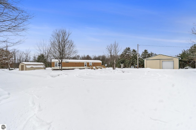 snowy yard with a garage and an outdoor structure