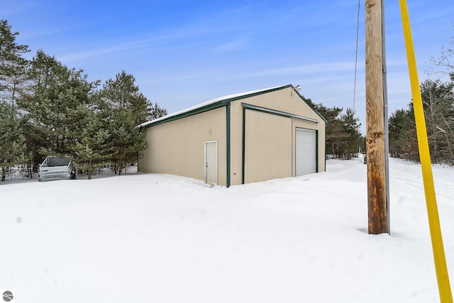 snow covered structure featuring a garage