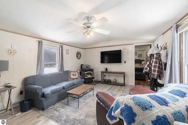 living room featuring ceiling fan, vaulted ceiling, hardwood / wood-style floors, and a wood stove