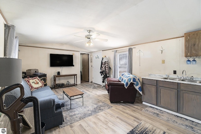 living room featuring vaulted ceiling, ceiling fan, sink, and light wood-type flooring