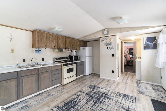 kitchen featuring sink, vaulted ceiling, light wood-type flooring, white appliances, and washer / clothes dryer