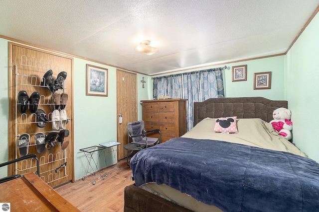 bedroom with hardwood / wood-style flooring, crown molding, and a textured ceiling