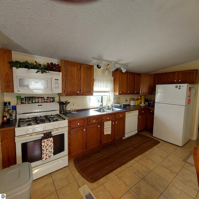 kitchen featuring light tile patterned flooring, sink, a textured ceiling, and white appliances