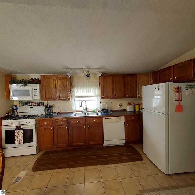 kitchen with white appliances, sink, a textured ceiling, and light tile patterned floors