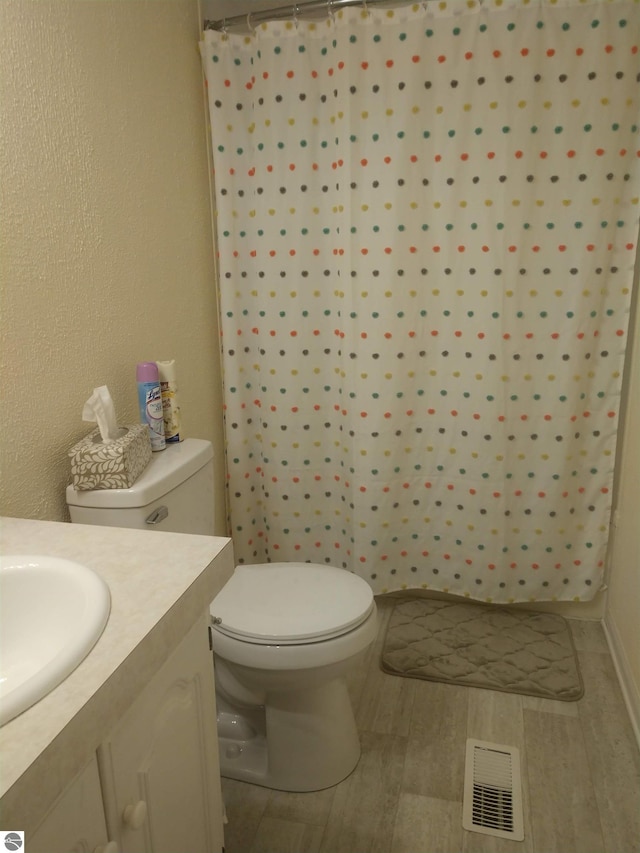 bathroom with hardwood / wood-style flooring, vanity, a shower with curtain, and toilet