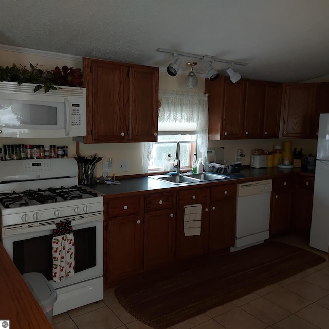 kitchen with sink, white appliances, light tile patterned floors, and a textured ceiling