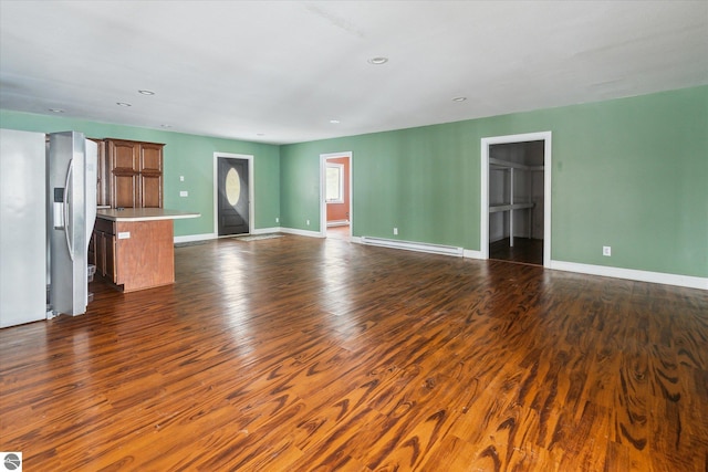 unfurnished living room featuring a baseboard heating unit and dark hardwood / wood-style floors