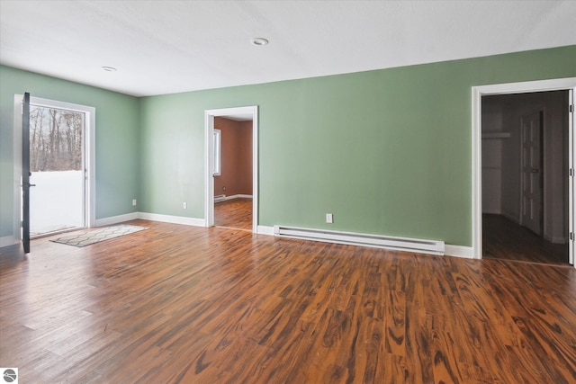 empty room featuring dark hardwood / wood-style floors and a baseboard heating unit