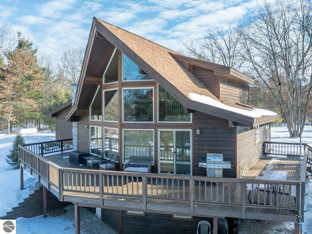 snow covered rear of property featuring a wooden deck