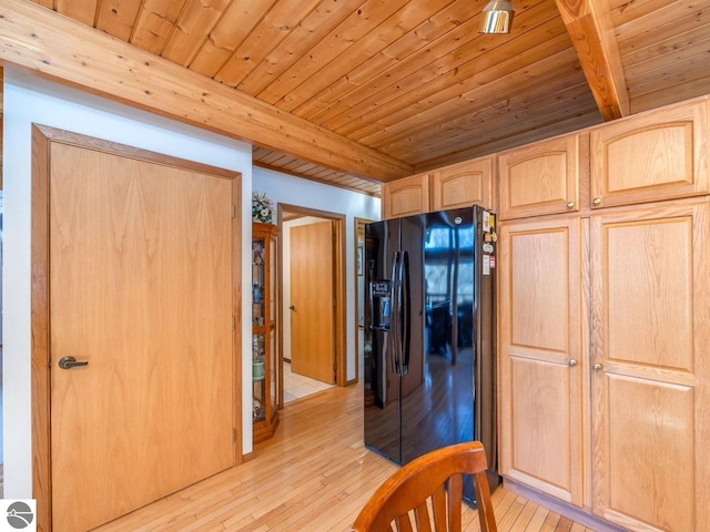 kitchen with light brown cabinetry, light hardwood / wood-style floors, beamed ceiling, and black fridge