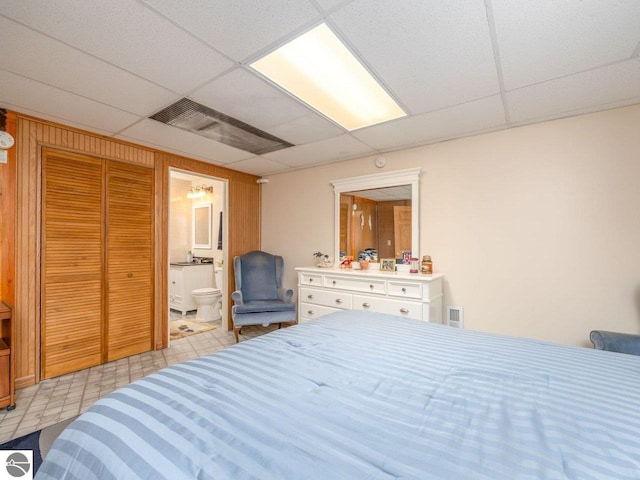 bedroom featuring ensuite bathroom and a paneled ceiling