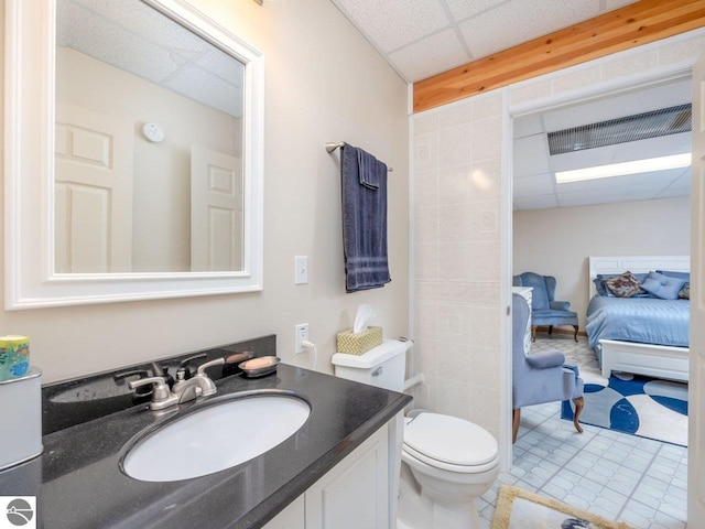 bathroom with vanity, toilet, and a drop ceiling