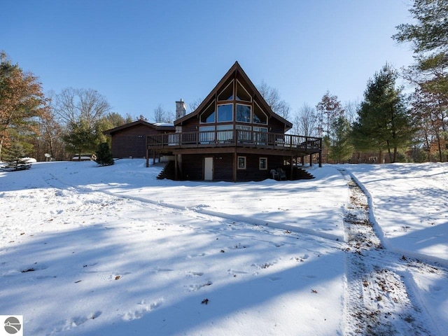 snow covered rear of property with a wooden deck