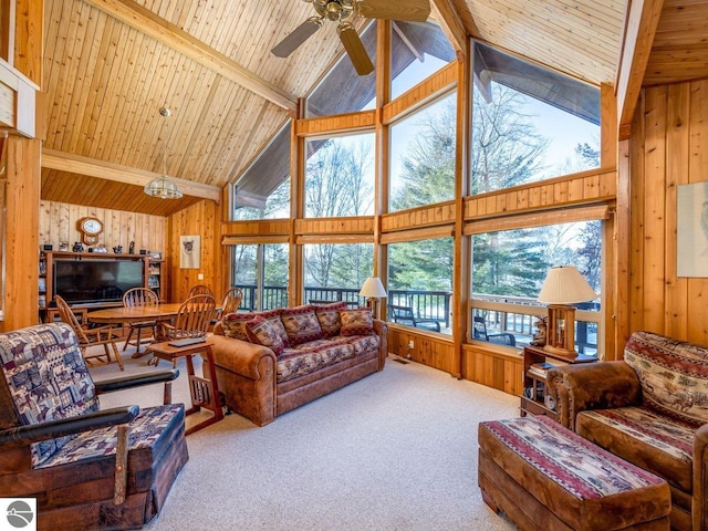 carpeted living room featuring beam ceiling, wood ceiling, ceiling fan, and wood walls