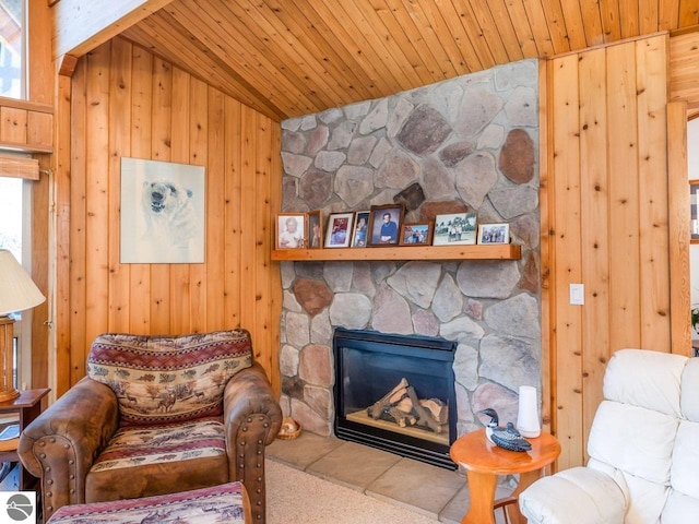 living area featuring lofted ceiling, wood ceiling, a stone fireplace, and wooden walls