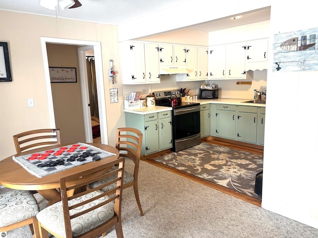 kitchen with sink, green cabinets, white cabinetry, hardwood / wood-style floors, and stainless steel range with electric cooktop