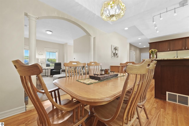 dining space with ornate columns, rail lighting, and light hardwood / wood-style floors