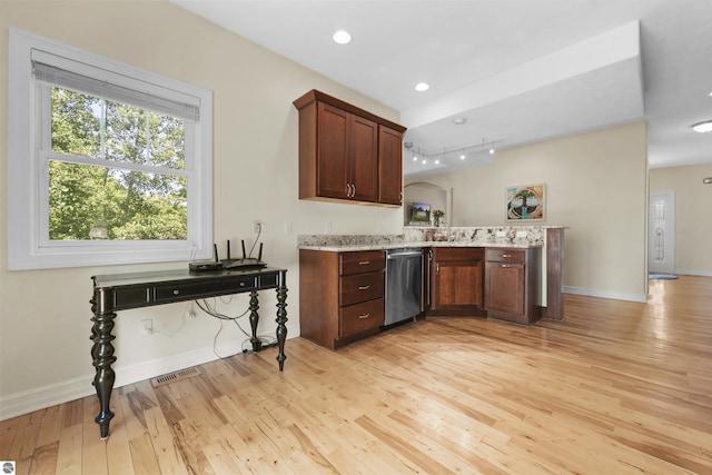 kitchen with light stone countertops, stainless steel dishwasher, light hardwood / wood-style floors, and kitchen peninsula