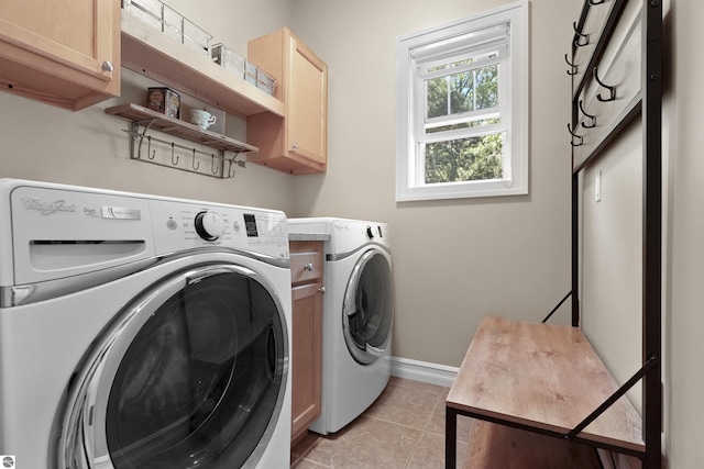 clothes washing area featuring cabinets, light tile patterned floors, and washer and clothes dryer