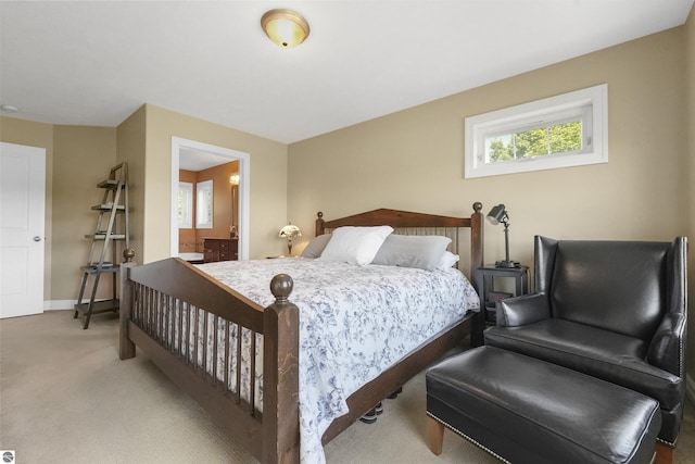 bedroom with ensuite bathroom and carpet flooring